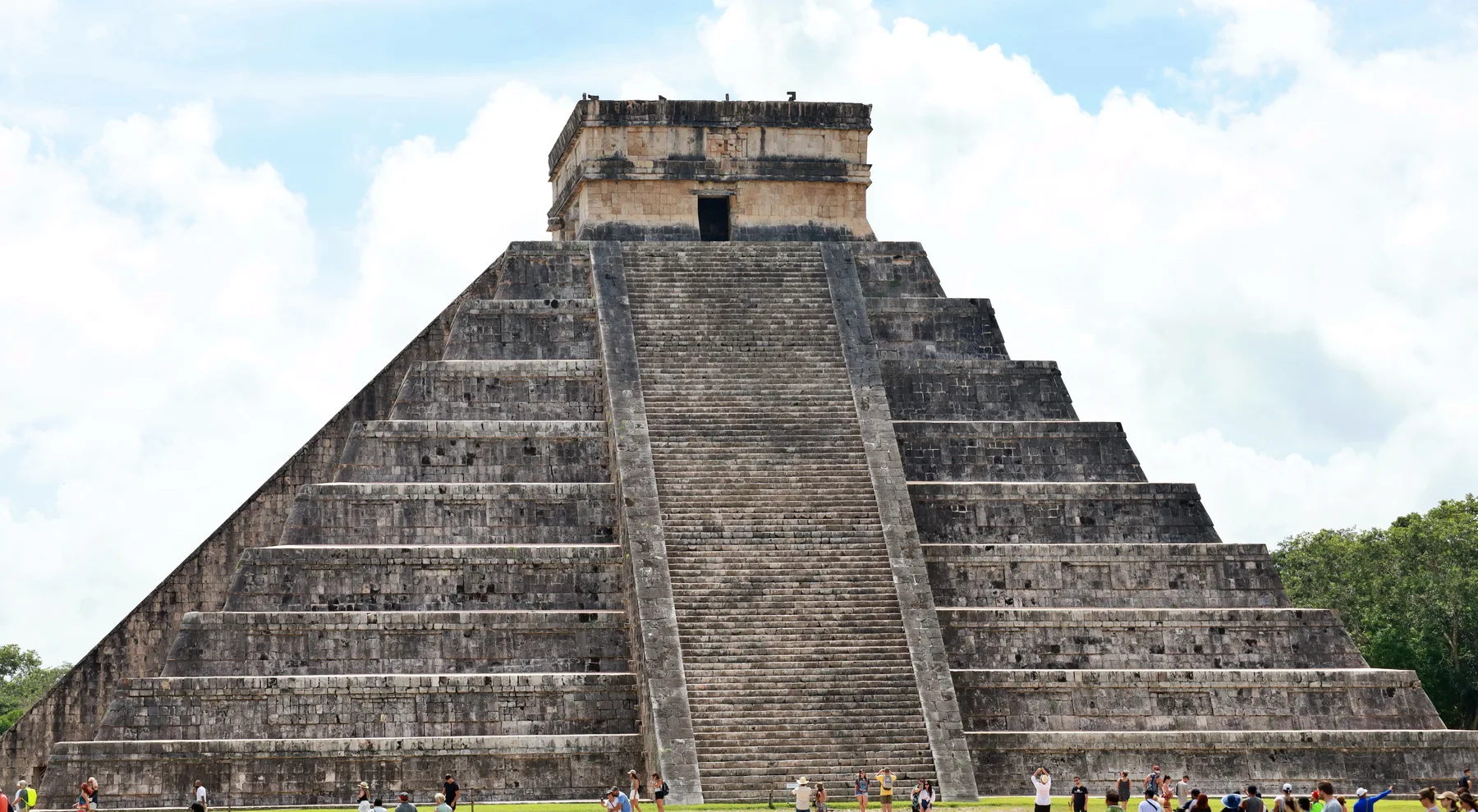 The stone pyramid at Chichén Itzá, with a broad central staircase beneath a cloudy sky.